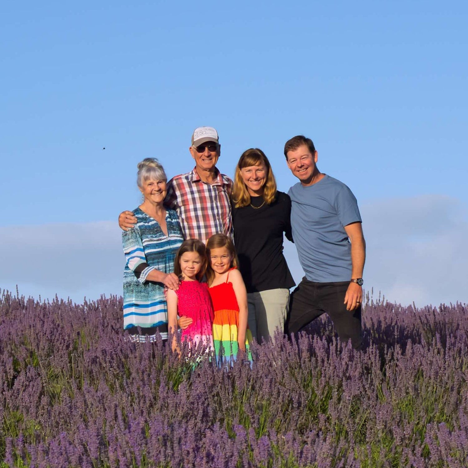 Family of six standing in a lavender field with a clear blue sky.